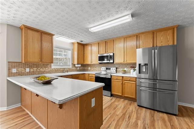 kitchen featuring decorative backsplash, stainless steel appliances, kitchen peninsula, and light wood-type flooring