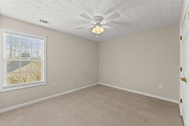 carpeted spare room with ceiling fan and a textured ceiling