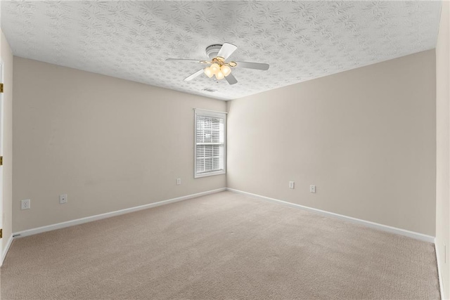 empty room with ceiling fan, light colored carpet, and a textured ceiling