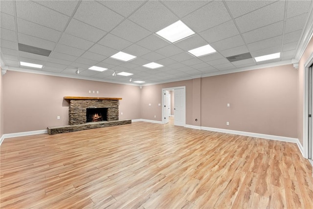 unfurnished living room with ornamental molding, a drop ceiling, a fireplace, and light hardwood / wood-style floors