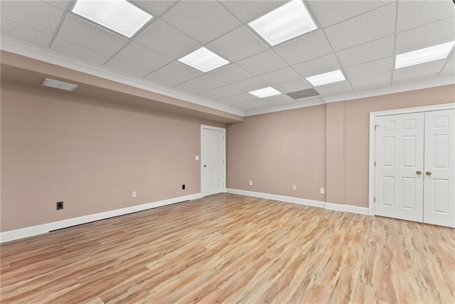 basement featuring a paneled ceiling and light hardwood / wood-style flooring