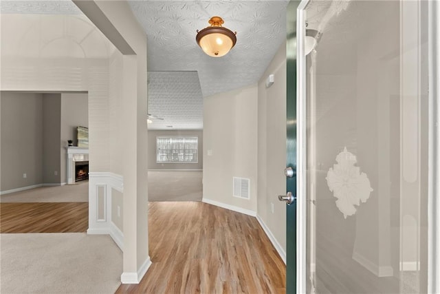 corridor featuring light wood-type flooring and a textured ceiling