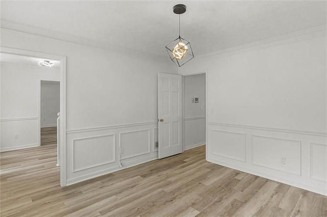 4220 Singing Post Ln NE, Roswell, GA 30075 - unfurnished dining area with crown molding, light wood-type flooring, a decorative wall, a chandelier, and wainscoting