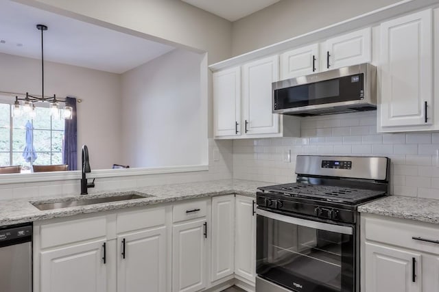 kitchen featuring appliances with stainless steel finishes, backsplash, a sink, and white cabinetry