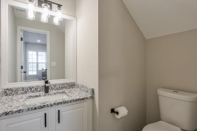 half bath featuring toilet, vaulted ceiling, and vanity