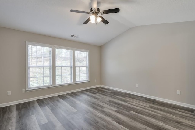 empty room with dark wood-style floors, lofted ceiling, visible vents, ceiling fan, and baseboards