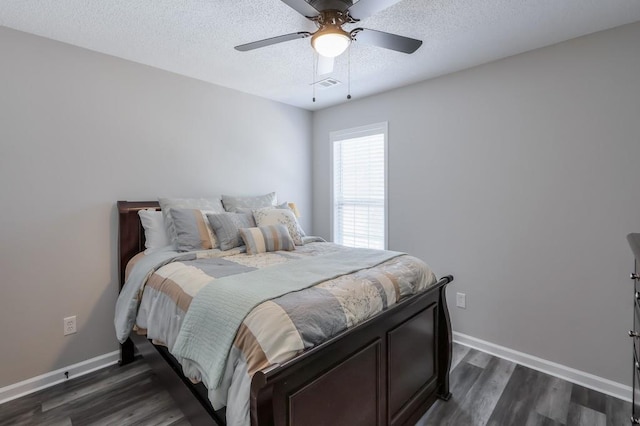 bedroom featuring baseboards, visible vents, dark wood finished floors, and a textured ceiling