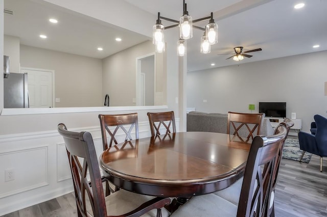 dining space featuring dark wood-type flooring, a decorative wall, a ceiling fan, and recessed lighting