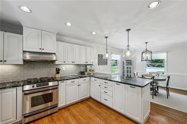 kitchen featuring under cabinet range hood, stainless steel gas range oven, ornamental molding, white cabinets, and light wood-style floors