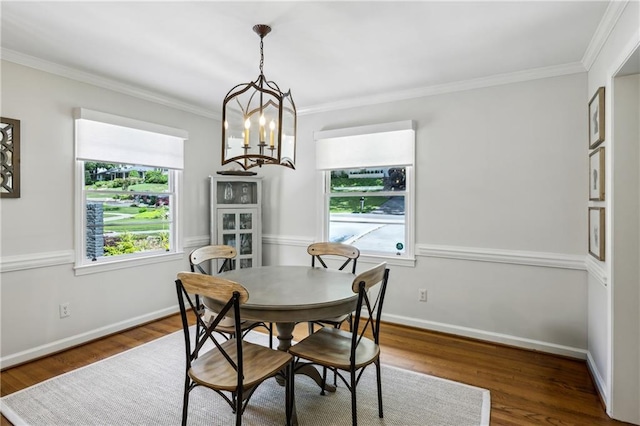 dining room with ornamental molding, wood finished floors, a chandelier, and baseboards