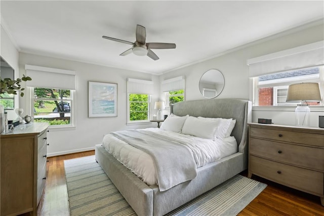 bedroom featuring multiple windows, crown molding, wood finished floors, a ceiling fan, and baseboards