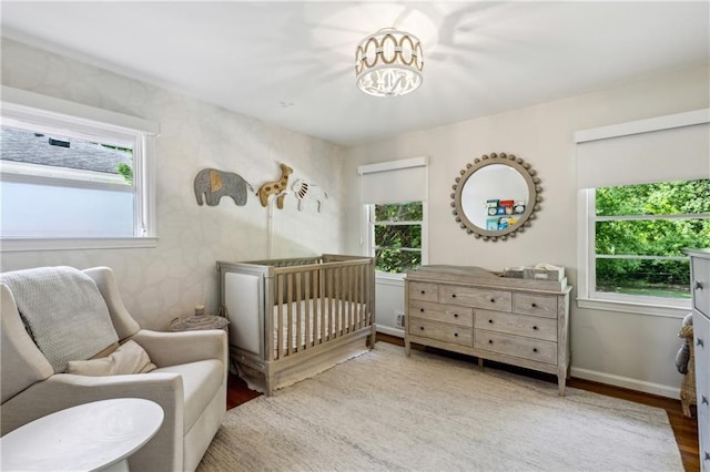 bedroom featuring wood finished floors, a nursery area, and baseboards