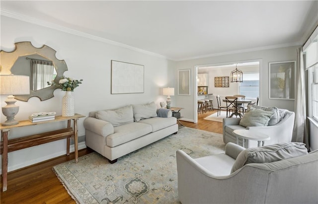 living area featuring crown molding, wood finished floors, baseboards, and a chandelier
