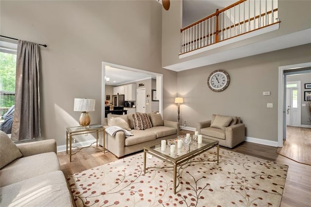 living room featuring a high ceiling, baseboards, and wood finished floors
