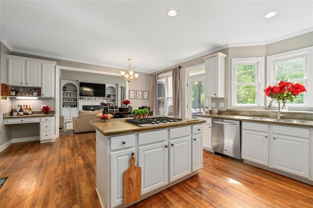 kitchen featuring stainless steel appliances, a sink, crown molding, a chandelier, and a center island