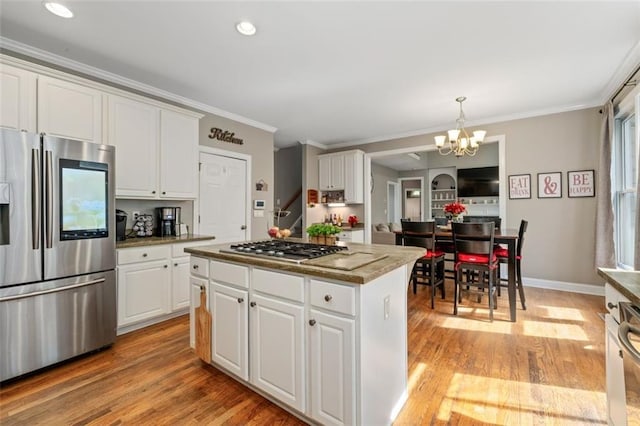 kitchen featuring appliances with stainless steel finishes, a kitchen island, crown molding, a chandelier, and white cabinets