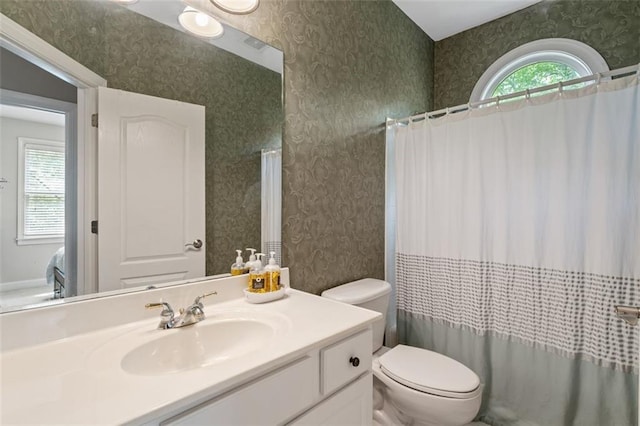 bathroom with wallpapered walls, toilet, vanity, and curtained shower