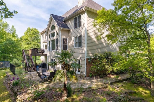 view of side of property featuring stairway, a deck, a patio area, and fence