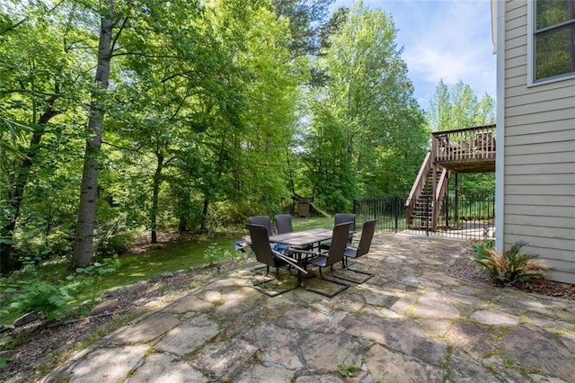view of patio / terrace with stairs, outdoor dining space, fence, and a wooden deck