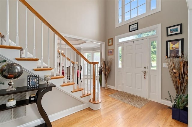 foyer featuring wood finished floors, baseboards, stairs, and a towering ceiling