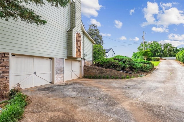 150 Wilbanks St, Buford, GA 30518 - view of home's exterior with an attached garage, concrete driveway, a chimney, and stone siding