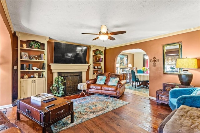 150 Wilbanks St, Buford, GA 30518 - living room featuring arched walkways, a textured ceiling, a ceiling fan, a fireplace with flush hearth, and crown molding