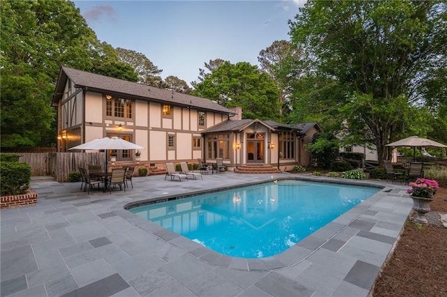 back of house with outdoor dining area, a patio area, fence, a fenced in pool, and stucco siding