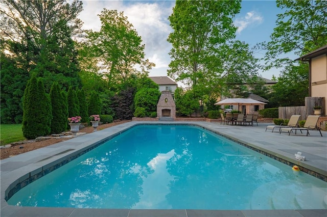 outdoor pool featuring a patio area, an outdoor stone fireplace, and fence