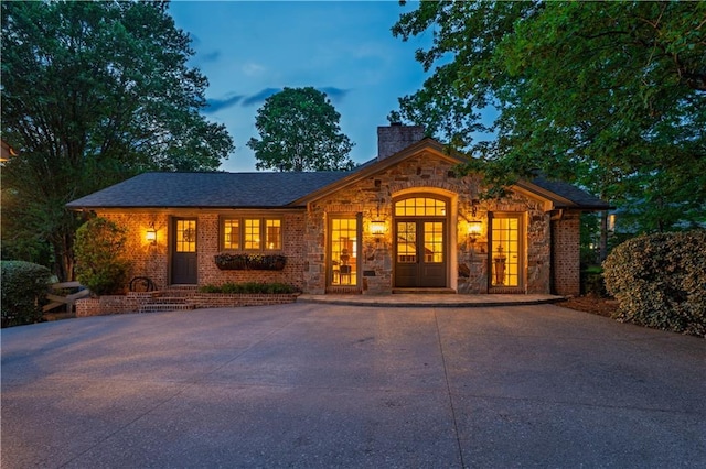 view of front of property with stone siding, driveway, and a chimney