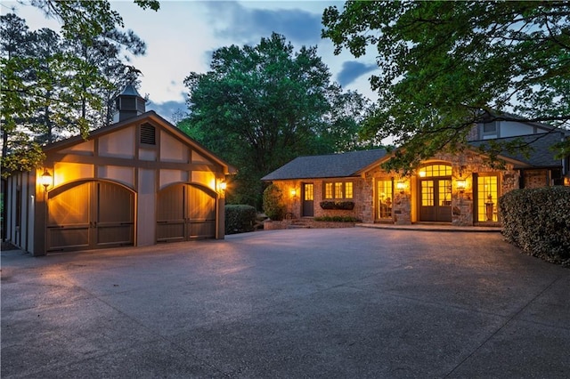 view of front of home with a garage, driveway, and stone siding
