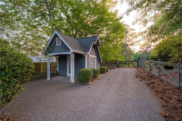 view of property exterior with a gate, roof with shingles, and fence