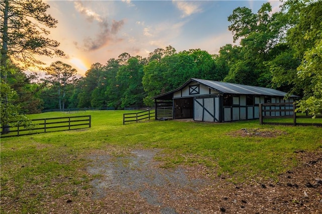 exterior space featuring a lawn, fence, a pole building, and an outbuilding
