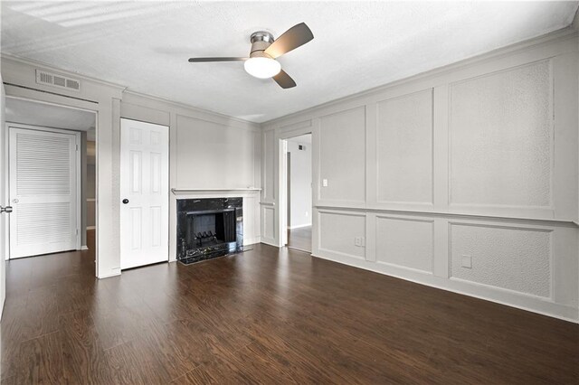 unfurnished living room featuring ceiling fan, a decorative wall, a premium fireplace, visible vents, and ornamental molding