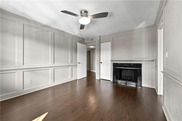 unfurnished living room with ceiling fan, dark wood-style flooring, a high end fireplace, a textured wall, and a decorative wall