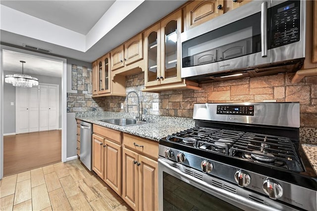 kitchen with backsplash, visible vents, light stone countertops, a sink, and stainless steel appliances