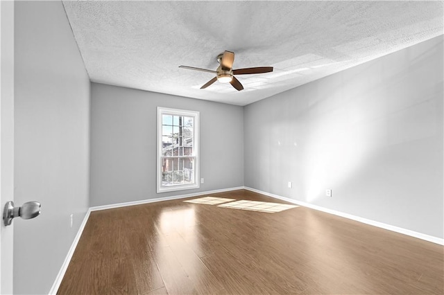 empty room with baseboards, a textured ceiling, ceiling fan, and wood finished floors