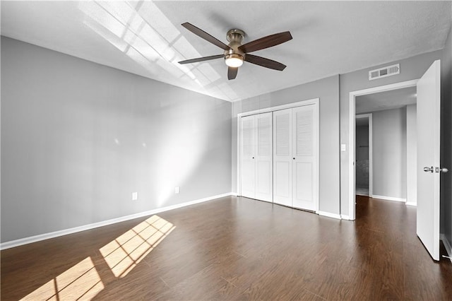 unfurnished bedroom with ceiling fan, visible vents, wood finished floors, baseboards, and a closet