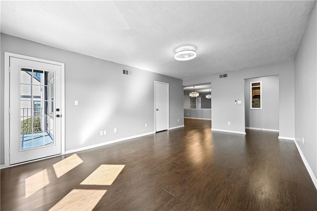 unfurnished living room featuring visible vents, baseboards, a textured ceiling, and wood finished floors