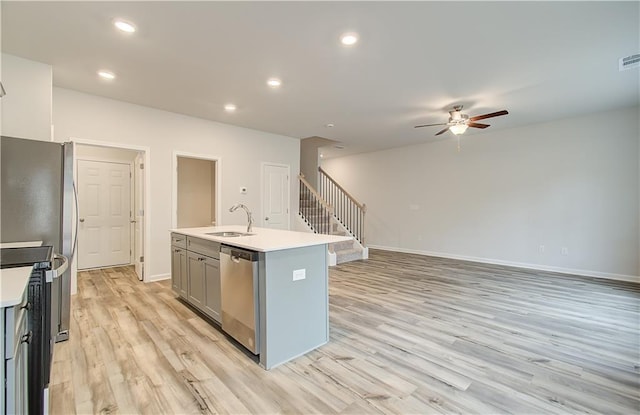 kitchen with an island with sink, sink, gray cabinetry, light hardwood / wood-style floors, and stainless steel appliances