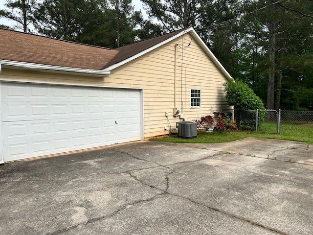 432 Manor Estates Dr, Stockbridge, GA 30281 - view of side of home with driveway, central AC unit, fence, roof with shingles, and an attached garage