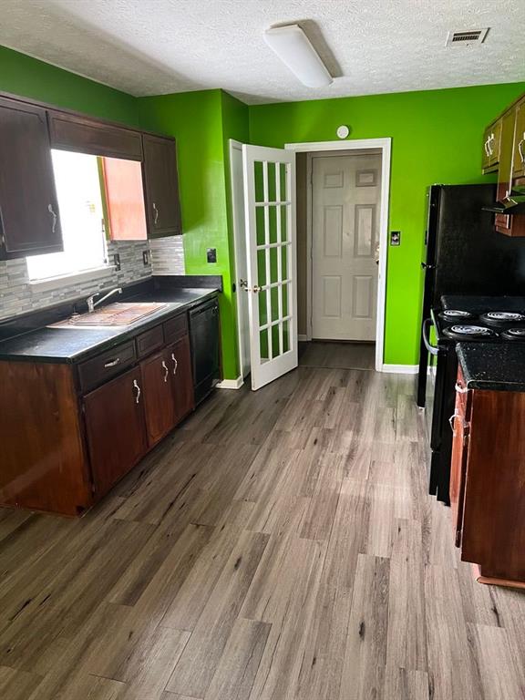 432 Manor Estates Dr, Stockbridge, GA 30281 - kitchen featuring black appliances, a sink, wood finished floors, a textured ceiling, and dark countertops