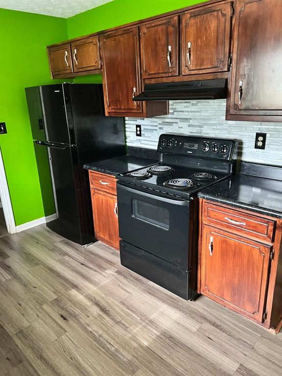 432 Manor Estates Dr, Stockbridge, GA 30281 - kitchen featuring black appliances, under cabinet range hood, light wood-style floors, and backsplash