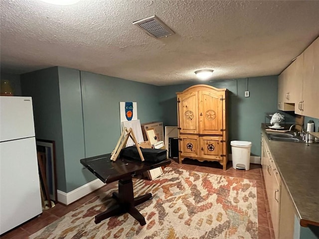 kitchen featuring white fridge, sink, and a textured ceiling