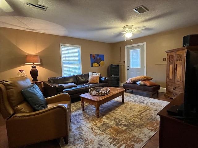 living room with a textured ceiling and ceiling fan