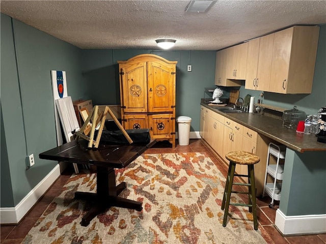 kitchen featuring sink, dark tile patterned flooring, a textured ceiling, and light brown cabinets