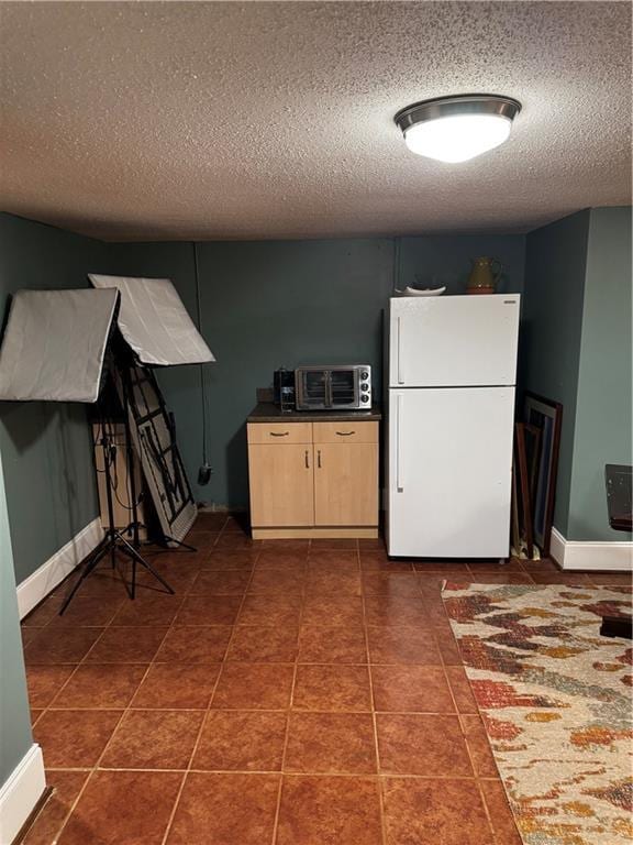 kitchen featuring dark tile patterned floors, a textured ceiling, and white refrigerator