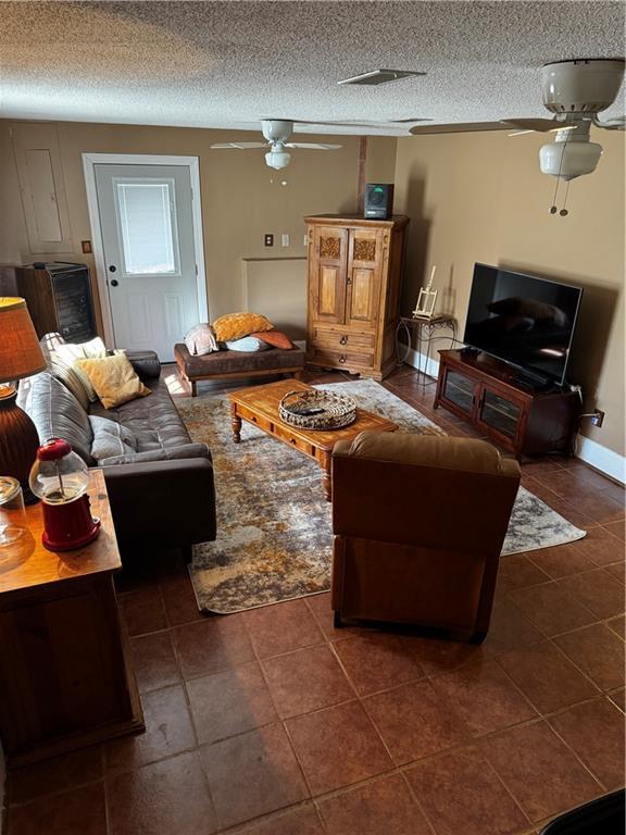 living room featuring dark tile patterned flooring, a textured ceiling, and ceiling fan