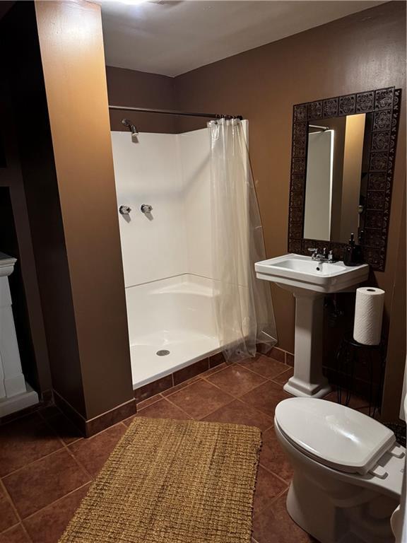 bathroom featuring walk in shower, toilet, and sink