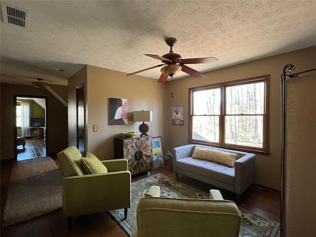 living room featuring dark hardwood / wood-style flooring, ceiling fan, and a textured ceiling