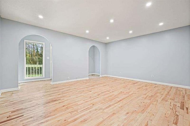 spare room featuring recessed lighting, baseboards, arched walkways, and light wood-type flooring